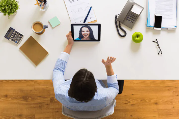 wanita memegang panggilan video dengan rekan kerja menggunakan tablet