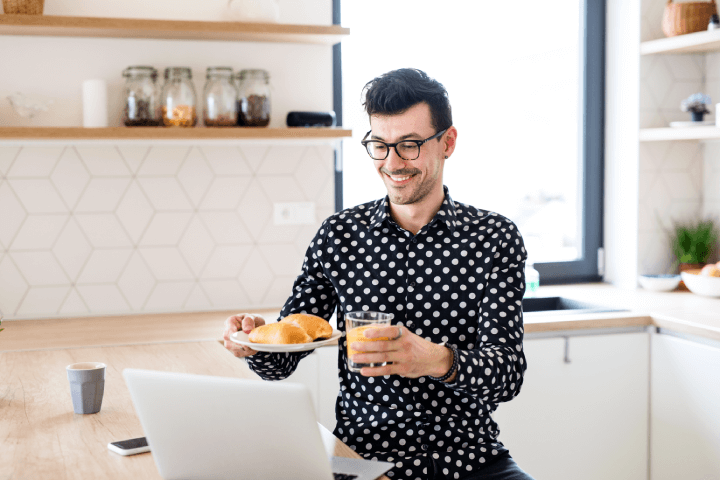 man working from home showing coworkers his breakfast