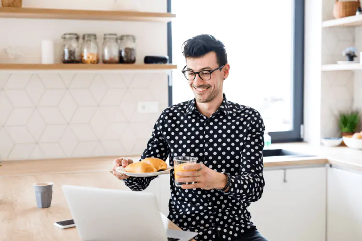 man working from home showing coworkers his breakfast