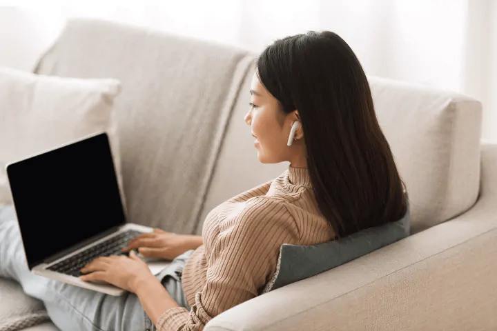 wanita belajar di laptop dari sofa
