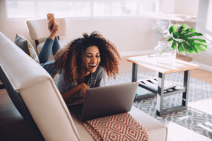 woman laughing while using messaging app on her laptop