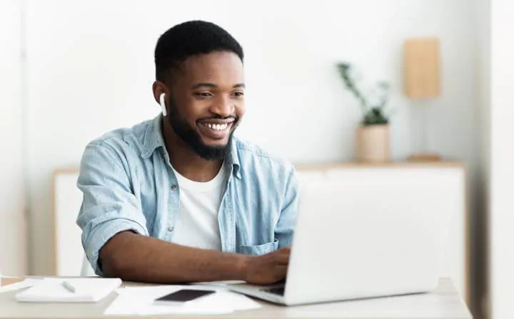 pria dengan earphone menggunakan laptop untuk belajar