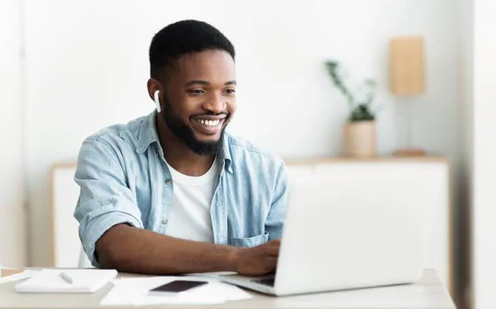 man with earphones using laptop to study