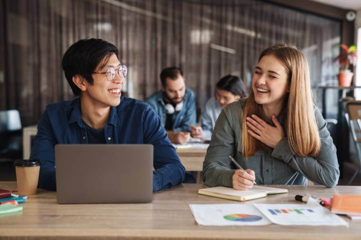 two students laughing in front of laptop