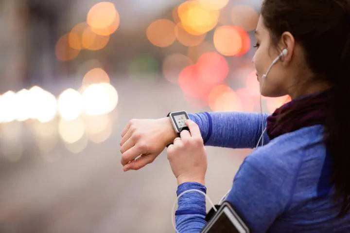 woman with headphones checking smartwatch