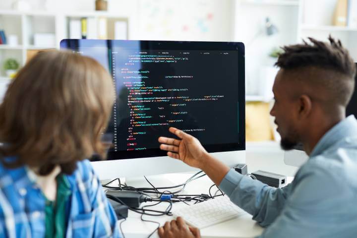 man shows employee computer screen with code