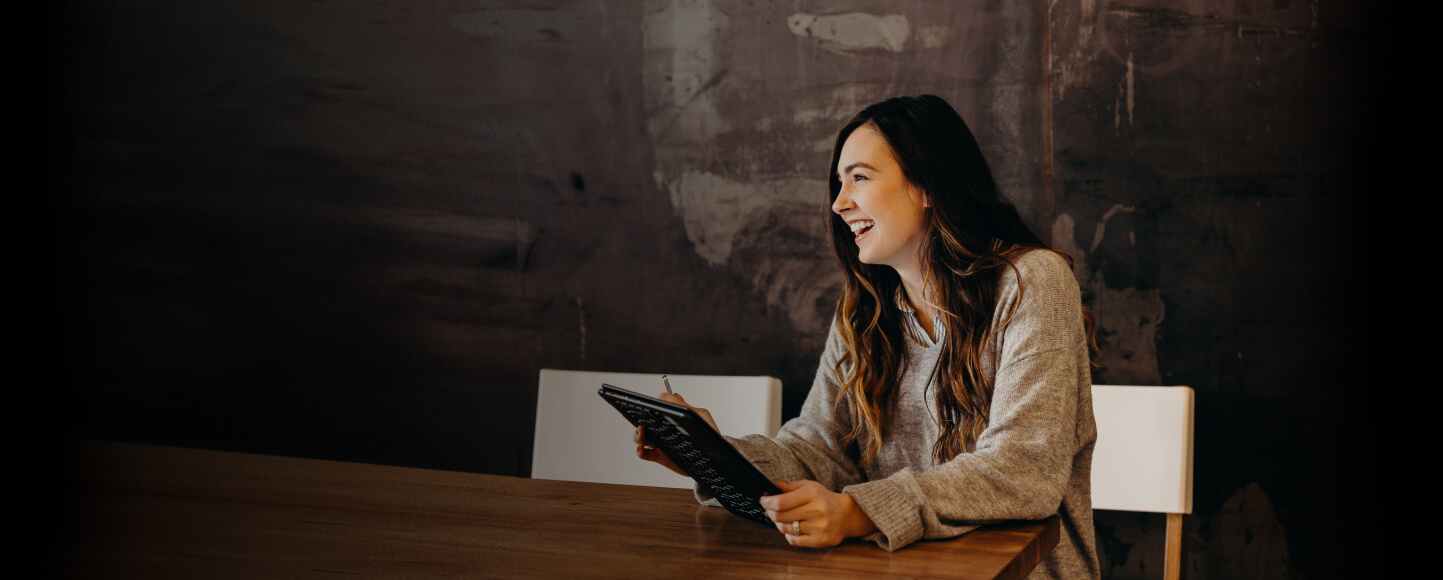 Smiling woman using an iPad at a table.